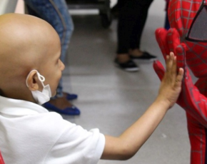 Paciente com câncer tocando a mão com homem fantasiado de Homem Aranha