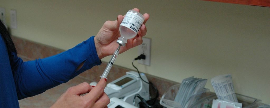 Homem retirando amostra de vacina com seringa