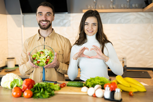 Nice guy and sweet girl with pretty smile are showing that they prefer vegetables to meat to save animals. They look healthy and happy being vegetarian. Healthy lifestyle.